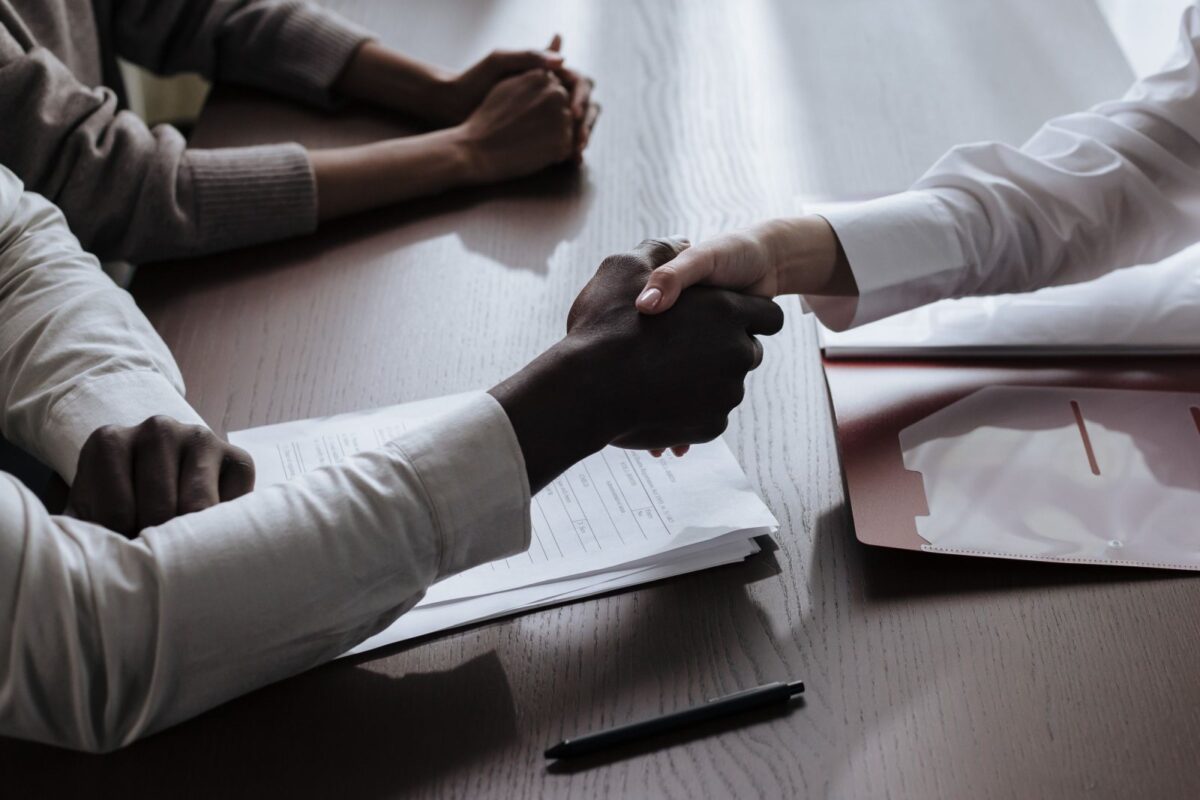 Two professionals shaking hands in an office after agreeing on a job offer.